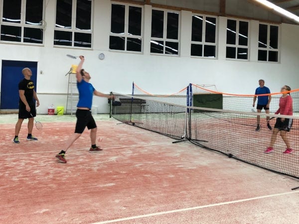 Vier Leute spielen Badminton.