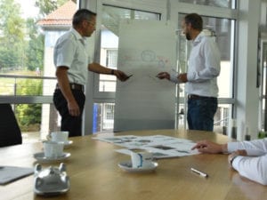 Zwei Personen stehen in einem Büro vor einem Flipchart.