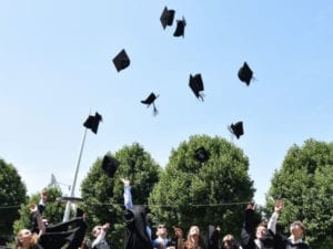 Mehrere Leute werfen ihre Absolventenhüte in die Luft