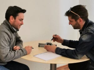 Two men look at a bearing and a screw.